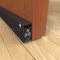 pemko 4301 dark bronze automatic door bottom surface mounted to the face of a wooden interior door with seal open